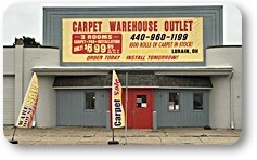 outside view of carpet warehouse sign sits overtop of two entrance doors that reads Carpet Warehouse Outlet